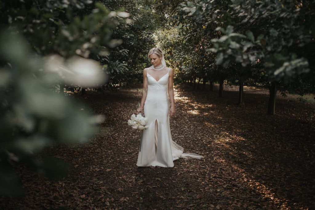 bride standing with flowers in forest