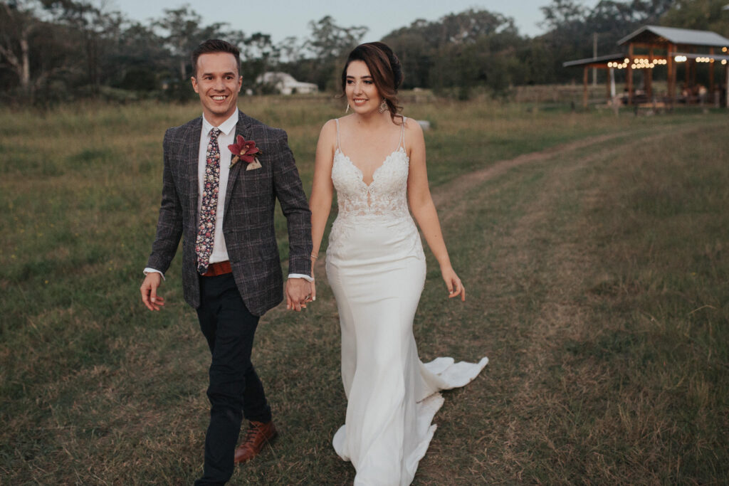 groom and bride walking holding hands at sunshine coast hinterland wedding