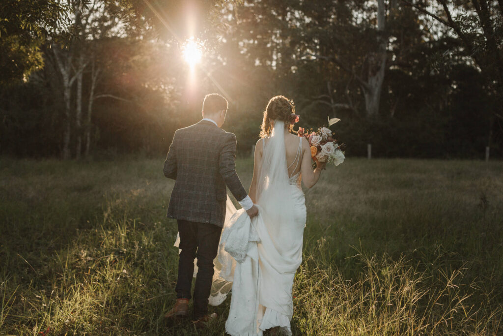 groom and bride walking at sunset at byron bay wedding