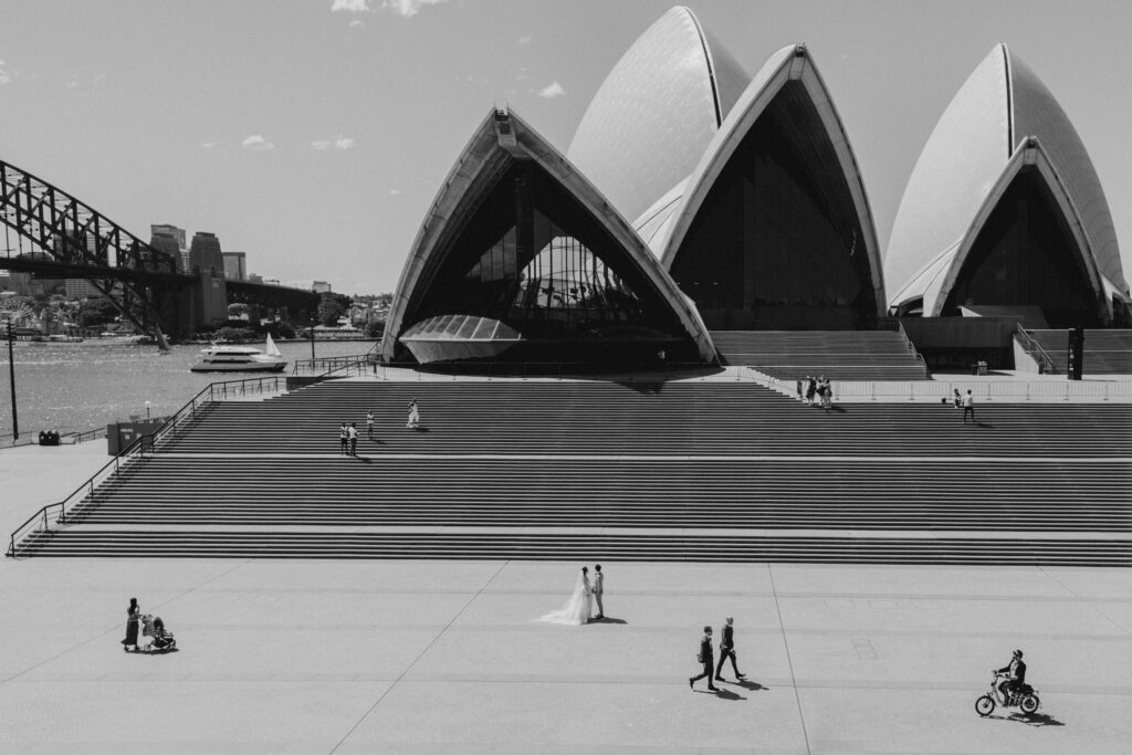 bride and groom standing in-front of opera house