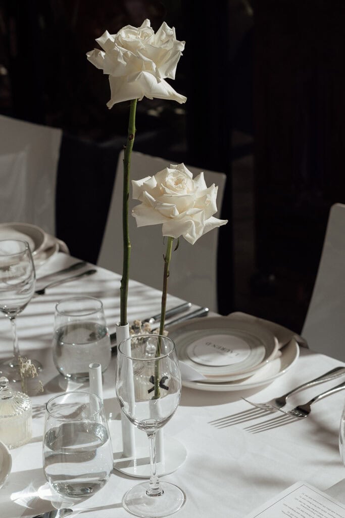 Sydney wedding photography - close-up of white roses in tall glass vases on a table.